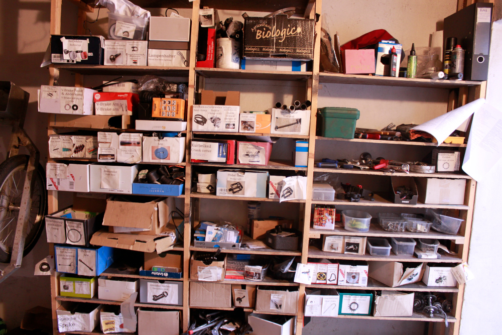 Overview of the bike workshop wall: many shelves and boxes with all sorts of things in them