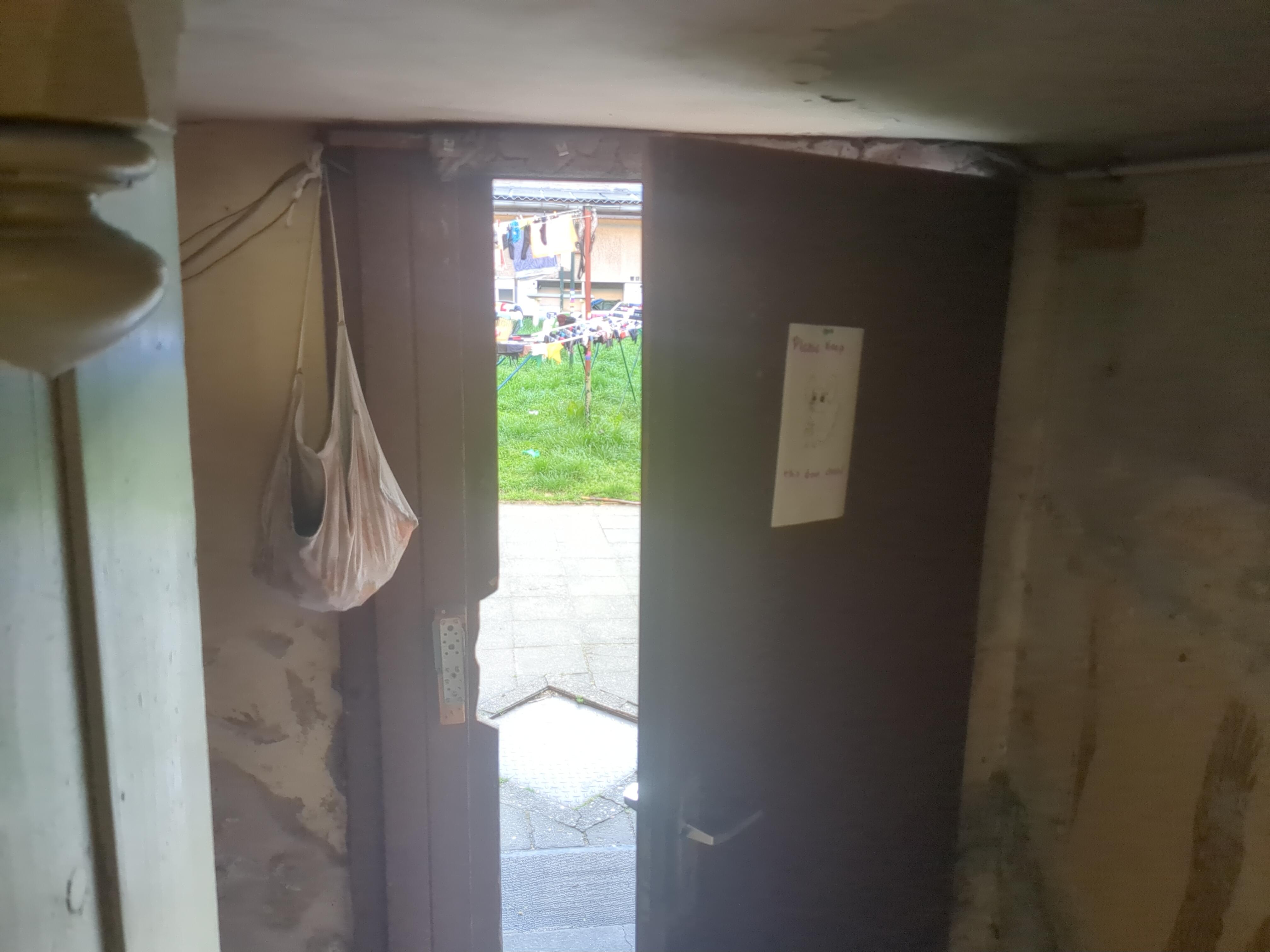 An open door out to the garden, with a sign saying “Please keep this door closed” and a mouse painted on it