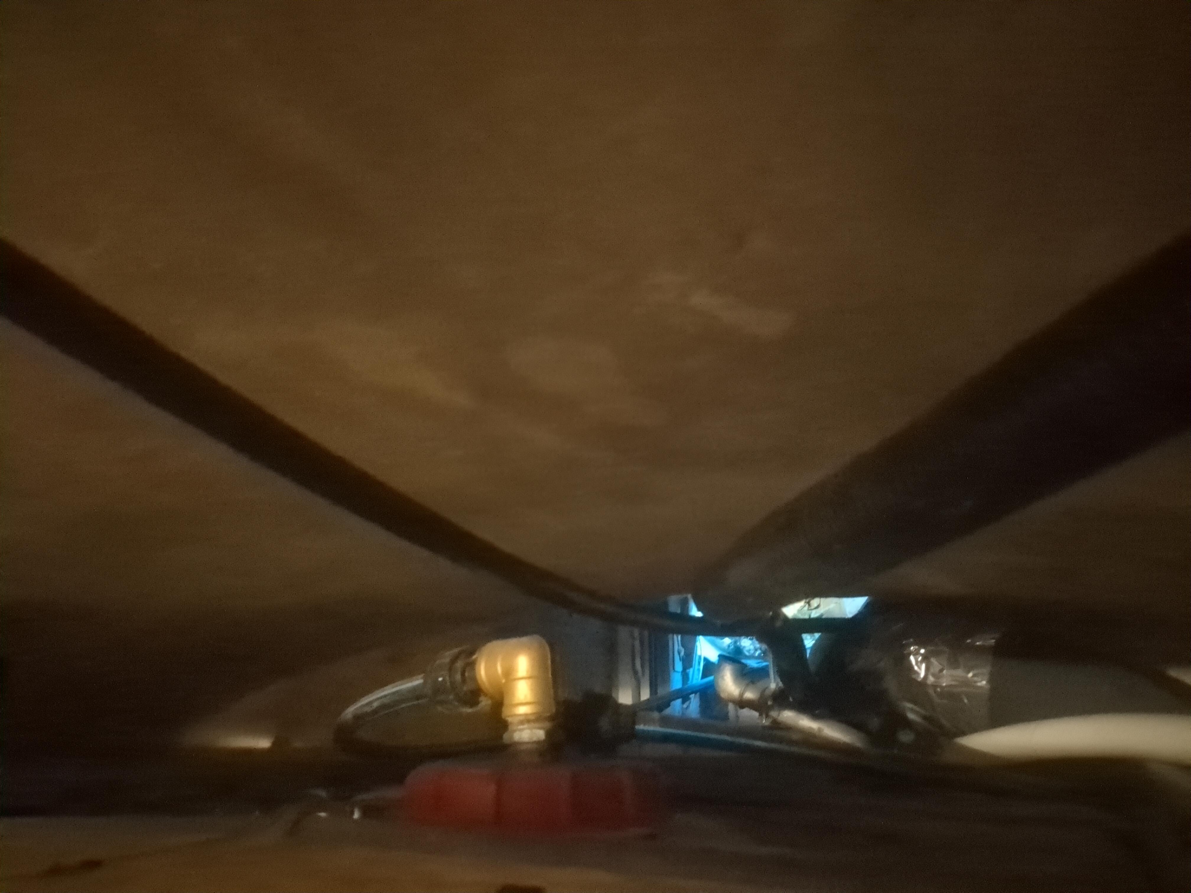 An opening in the wall behind hoses and an IBC canister